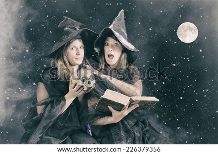 two halloween witches saying a magic formula to poison an apple