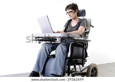 Mature disabled woman working on a laptop in a wheelchair - stock