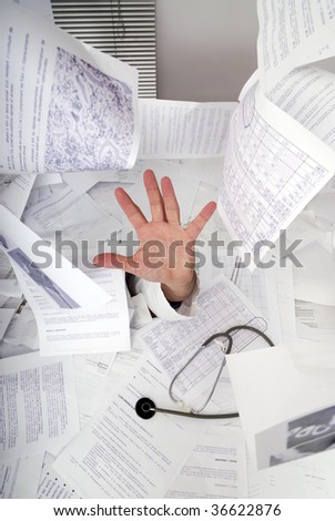 hand of doctor sticking out of a desk full of papers
