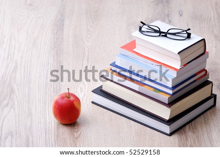 stack of books with apple and glasses