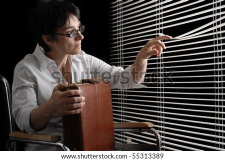 Waiting disabled business woman in wheelchair looking trough closed blinds
