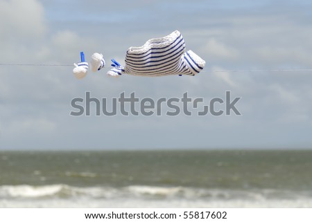 navy baby sweater and booties hanging on a clothes line in front of the sea