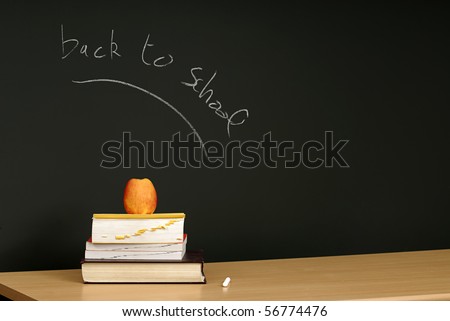 Back to school written on blackboard, desk with books and apple