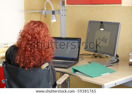 Disabled woman in wheelchair working on the computer at her desk