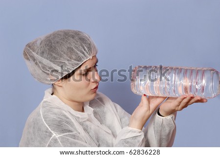 female factory worker in the bottling industry inspection a water bottle against a blue background