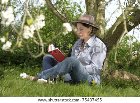 woman reading a book under a tree in the garden