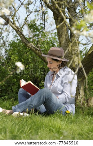 woman reading a book under a tree in the garden