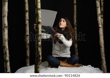Despaired young woman in the snow with laptop searching for a connection