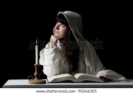 young woman reading with candle light on dark background