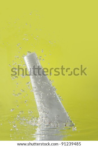 splash of cosmetic bottle falling in water on green background