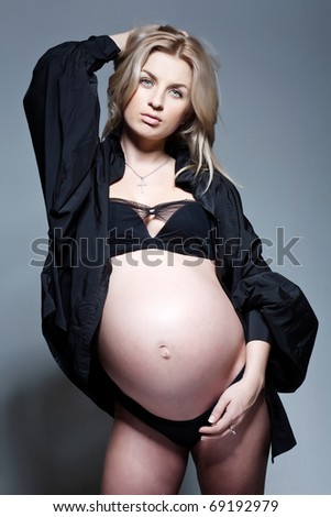 portrait of serious pregnant woman in black shirt in studio