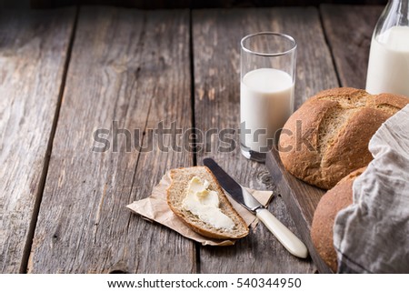 Rustic breakfast with wholegrain bread, milk and butter on wooden background. Copy space