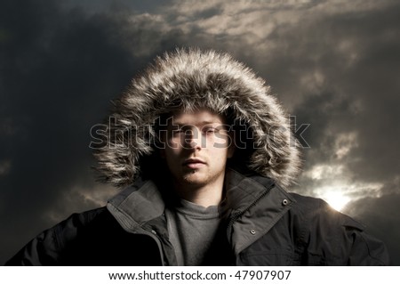Modeling portrait, wearing fur hooded parka coat with moody sky. Expedition adventurer.