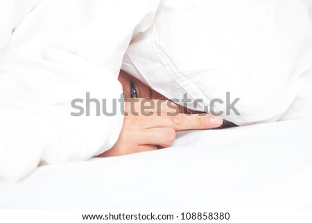 woman in bed under blanket shows the middle finger