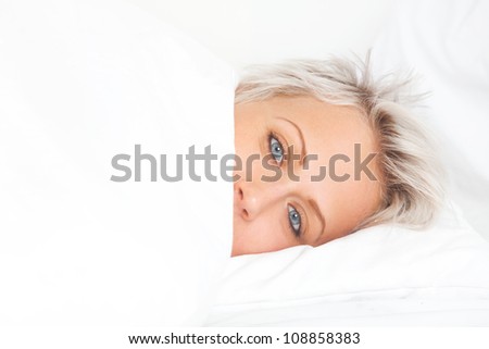 young woman in bed under white blanket