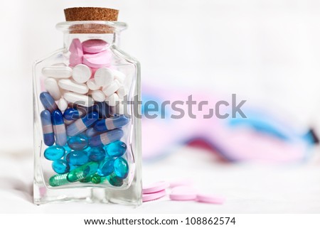 Different pills in a glass bottle and sleeping mask on the background
