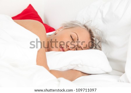 Beautiful young woman sleeping in bed, over white