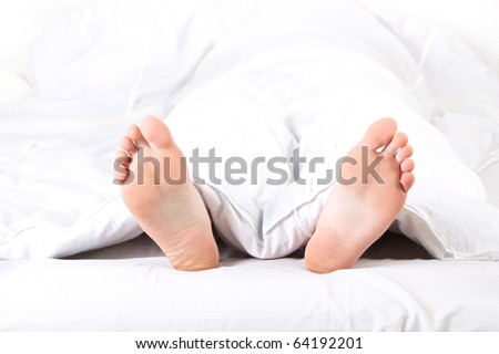 Men\'s feet under a white blanket