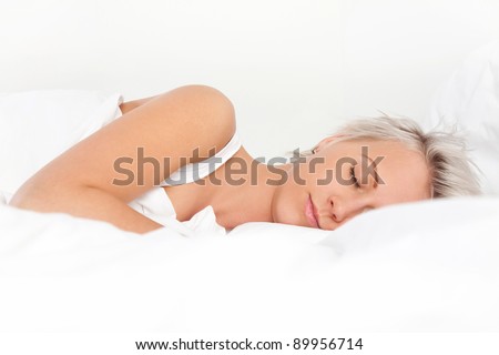 Beautiful young woman sleeping in bed, over white