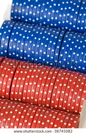 Closeup of red and blue poker chips in their clear plastic case, isolated on white.