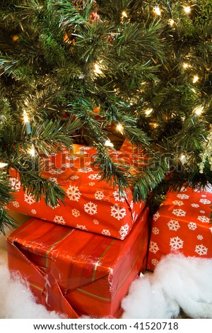 A closeup of Christmas presents under the tree, focus on the worn wrapping paper, indicating it has been re-used for multiple christmas\'.