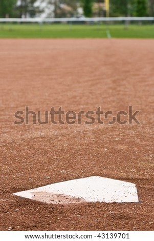A closeup of home plate at a baseball diamond, looking out at the first base line towards the outfield.