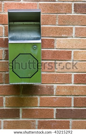 A small garbage for cigarettes, affixed to a red brick wall.
