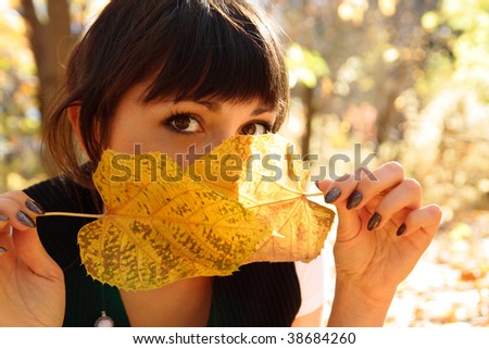 woman hides the face behind autumn leaves