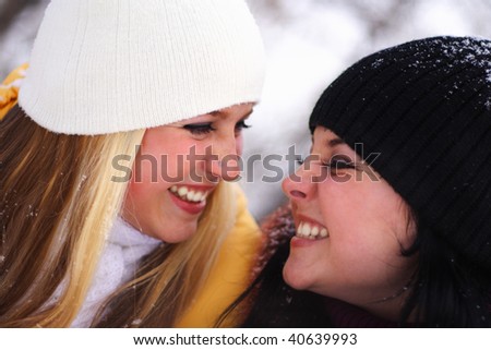 two happy, young girls smile and look against each other