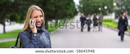 happy young woman speaks by phone on the street