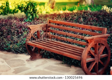 Beautiful wooden bench is in a park on the ornamental bushes