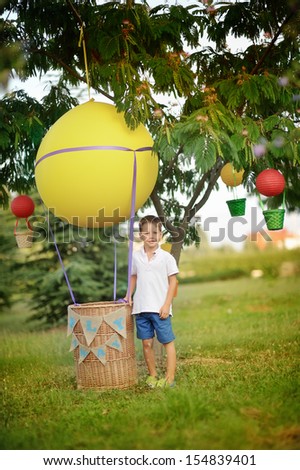 on the green grass boy stands near a hot air balloon with a basket