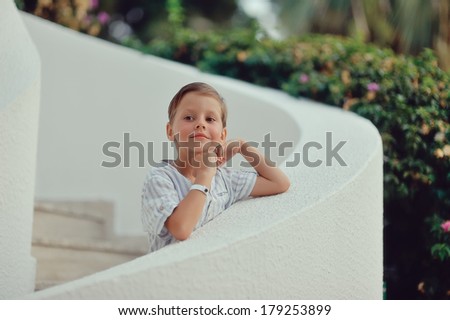 cute little boy in white shirt standing on white stairs