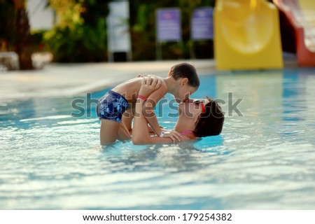 Mom and son having fun in the summer playing in the pool