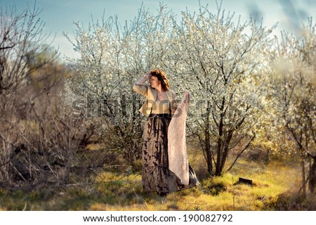 in the garden with flowering trees posing woman with a scarf in a long skirt