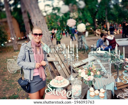 girl in the woods at the fair beautifully decorated cakes and cookies on wooden racks