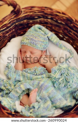 in a wicker basket brown cute sleeping baby in a blue cap with a large bubo