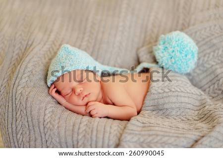 in bed sleeping baby in a blue cap with a large bubo