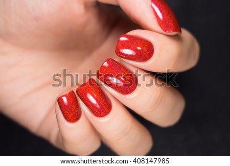 Woman with beautiful manicured red fingernails gracefully crossing her hands to display them to the viewer on a white background in a fashion, glamour and beauty concept