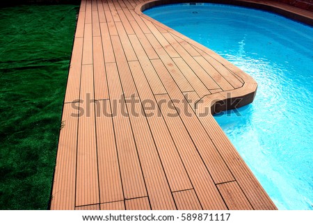 Backyard with swimming pool and composite material brown deck and blue water