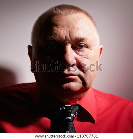 Dramatic close up portrait of middle aged business man in red shirt and tie