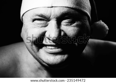Close up black and white portrait of laughing mature man in Santa Claus hat