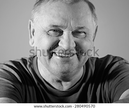 Black and white portrait of cheerful aged man in t-shirt smiling with dimples