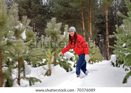 Happy pretty young woman in the red jacket is selecting a tree.