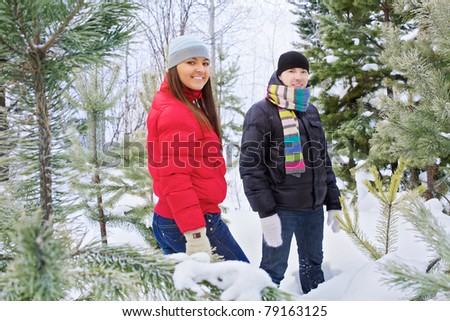 Happy young woman and man standing in snow fir forest outdoor