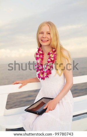 Pretty young woman in white dress with tablet PC on ship at sea