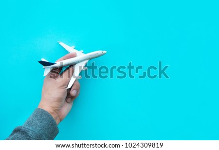 Male hand holding model plane,airplane on blue pastel color background.