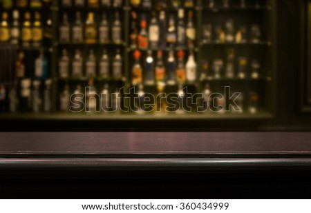 Empty the top of wooden table with  blurred counter bar and  bottles Background /for your product display