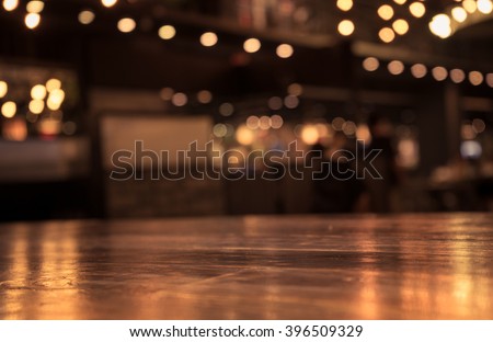 Empty wood table top and  blur of cafe restaurant in dark  night background/selective focus .For montage product display