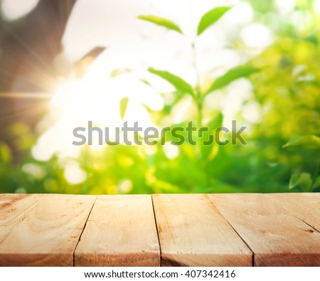 Empty of wood table top on blur of fresh green abstract from garden with sunlight .For montage product display or design key visual layout